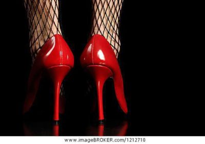 Woman in fishnet stockings and red high heel shoes isolated on black background
